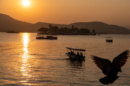 India. Rajasthan. Udaipur. Sunset on Lake Pichola where tourist boats sail with the Jag Mandir, also called the "Lake Garden Palace", a palace built on an island in the backgroundの写真素材