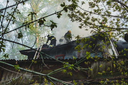 Firefighters extinguished the fire at an old house caught fireの写真素材