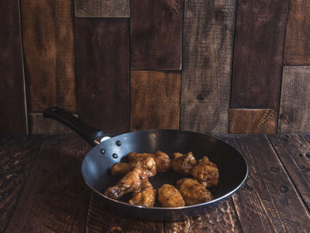 Chicken wings in a frying pan with fresh tomatoの写真素材