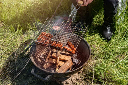 Sausages are fried on the grill on an open fireの写真素材