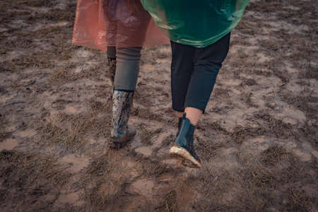 In rubber boots on dirt, at the festival
