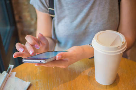 A girl is sitting with a phone in a cafe, a coffee house