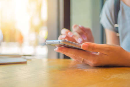 A girl is sitting with a phone in a cafe, a coffee house