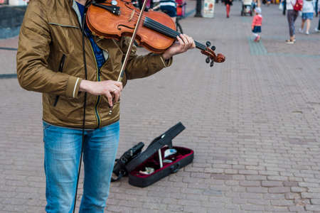 Street violinist plays the violin at noon, autumn dayの写真素材
