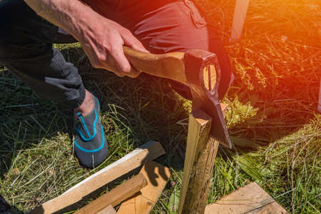 A man chops firewood on a hike summer day