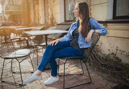 Beautiful girl in jeans suit, in a summer cafe on a sunny dayの写真素材