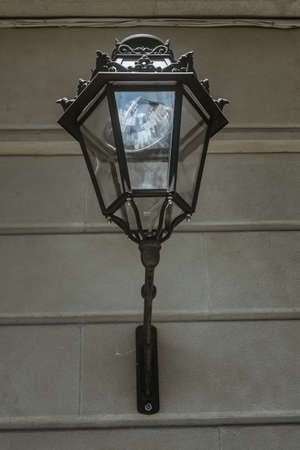 Vintage street lamp on the concrete wall of an old building. Summer day
