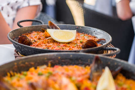 Delicious seafood paella on an iron pan. Rice, lemon, mussels, shrimp and vegetablesの写真素材
