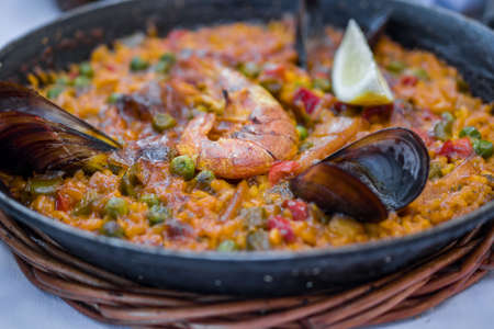 Delicious seafood paella on an iron pan. Rice, lemon, mussels, shrimp and vegetablesの写真素材
