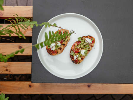 Delicious bruschetta with a variety of fillings. On a white plate with sauceの写真素材