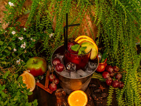 Red alcoholic cocktail in a bucket with ice. Garnished with fruits and berries on a wooden table. Tropical flavorの写真素材