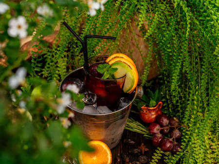 Red alcoholic cocktail in a bucket with ice. Garnished with fruits and berries on a wooden table. Tropical flavorの写真素材