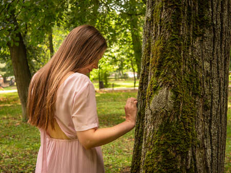 Mom and daughter walk and play in the park. Dressed in dresses. Sunny summer day, weekend in a city park.の写真素材