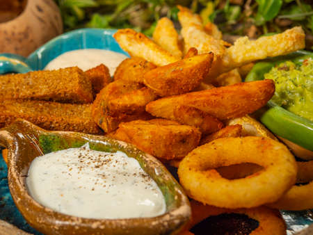 Plate with snacks for beer. French fries, cheese sticks, onion rings and white sauce.の写真素材