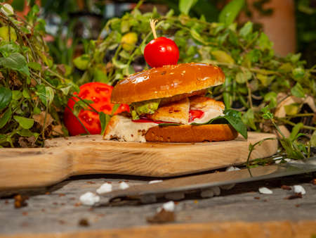 Juicy burger on a wooden board. Hamburger with tomatoes and bacon with white sauce.の写真素材
