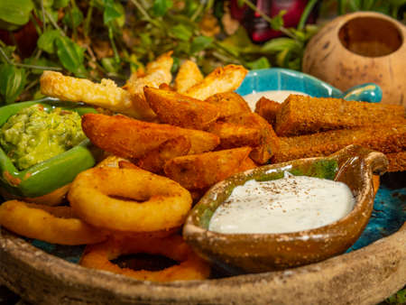 Plate with snacks for beer. French fries, cheese sticks, onion rings and white sauce.の写真素材