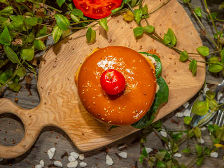 Juicy burger on a wooden board. Hamburger with tomatoes and bacon with white sauce.の写真素材