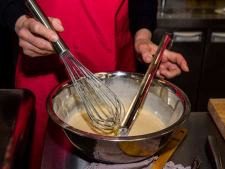 The process of making pancakes. Cook in the kitchen makes the dough.