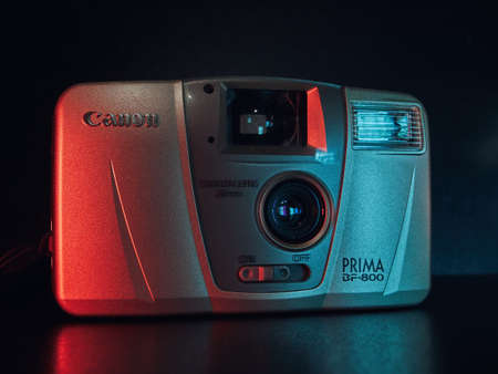 A compact Canon film camera lies on a table, close-up photograph. Ligh