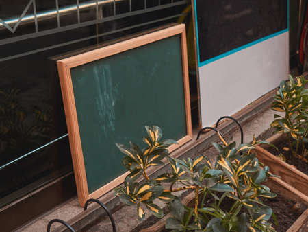 A small chalk board and plants in a pot on the window of a small cafe. Summerの写真素材