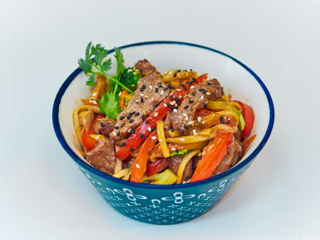 Udon noodles with meat in a plate on a white surface.の写真素材