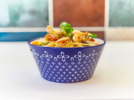 Udon noodles with seafood in a plate on a white surface.の写真素材
