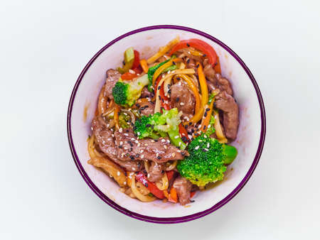 Udon noodles with meat in a plate on a white surface.の写真素材