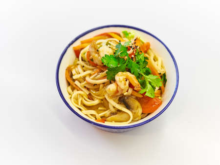 Udon noodles with seafood in a plate on a white surface.の写真素材