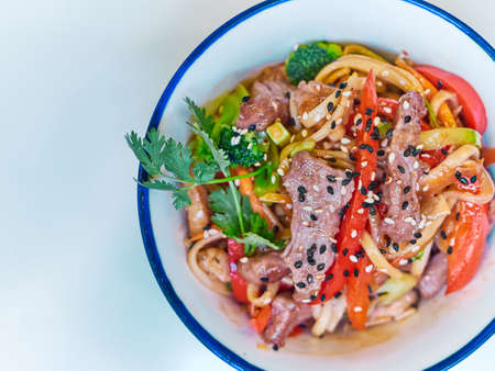 Udon noodles with meat in a plate on a white surface.の写真素材