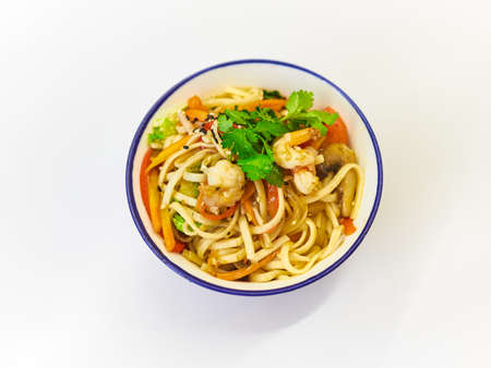 Udon noodles with seafood in a plate on a white surface.の写真素材