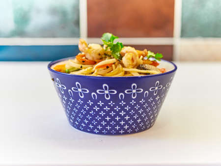 Udon noodles with seafood in a plate on a white surface.の写真素材