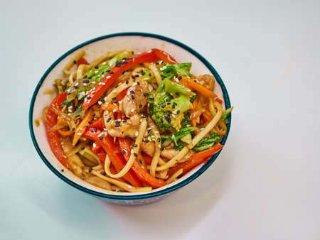 Udon noodles with meat in a plate on a white surface.の写真素材