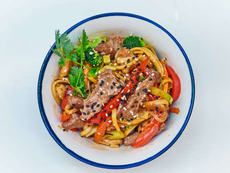 Udon noodles with meat in a plate on a white surface.の写真素材