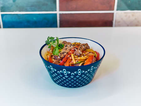 Udon noodles with meat in a plate on a white surface.の写真素材