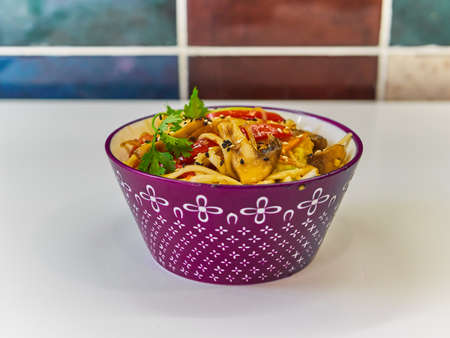 Udon noodles with meat in a plate on a white surface.の写真素材