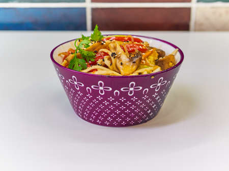 Udon noodles with meat in a plate on a white surface.の写真素材