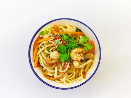 Udon noodles with seafood in a plate on a white surface.の写真素材