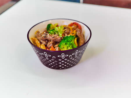 Udon noodles with meat in a plate on a white surface.の写真素材