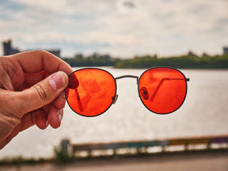 Old red sunglasses in hand. Scratched glass. Dayの写真素材