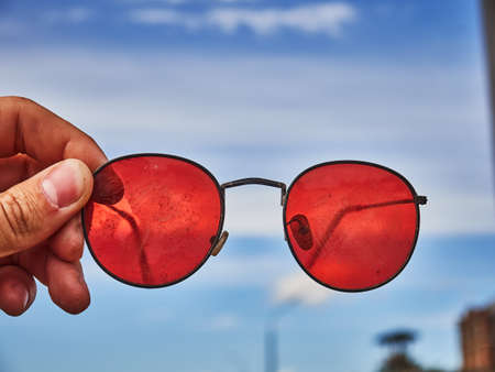 Old red sunglasses in hand. Scratched glass. Dayの写真素材