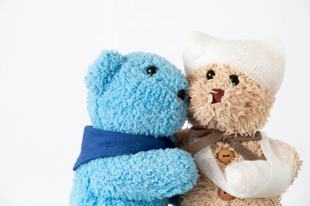Teddy bear with trauma of the head and bandaged arm ,Young teddy bear nurse is taking care of loverの写真素材