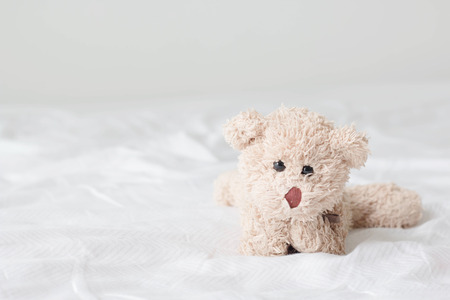 Teddy bear lying down relaxing on bedの写真素材