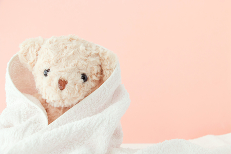 Teddy bear covered by a towel on pink pastel background,Cute teddy bear covered towel after bathの写真素材