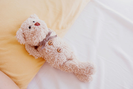 Cute little teddy bear lay down on the bed.の写真素材