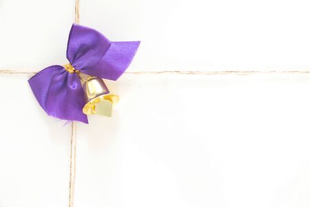Gift box, decorated with a purple bow with a golden bell.の写真素材