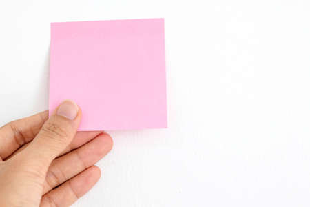 Pink sticky notes in my hand for appointments and put them on the white wall background.