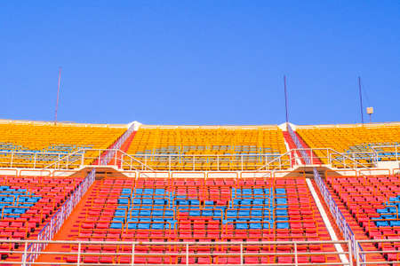 red and yellow Rows of empty seat in football stadium with blue sky backgroundのeditorial素材