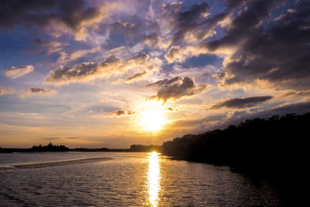 Beautiful blazing sunset landscape at black sea and orange sky above it with awesome sun golden reflection on calm waves as a background. Amazing summer sunset view on the beach.の写真素材