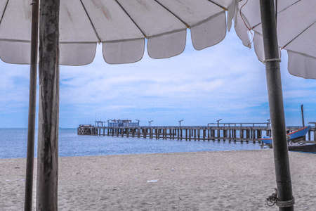 Pair of sun loungers and a beach umbrella on a deserted beach; perfect vacation concept with blue sky and cloud backgroundの写真素材