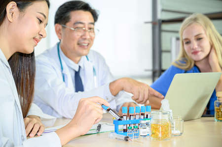 Group of doctors wearing formal white coat and blue scrubs suit, Teamwork brainstorm meeting with computer laptop at the hospital. Healthcare specialist people.の写真素材